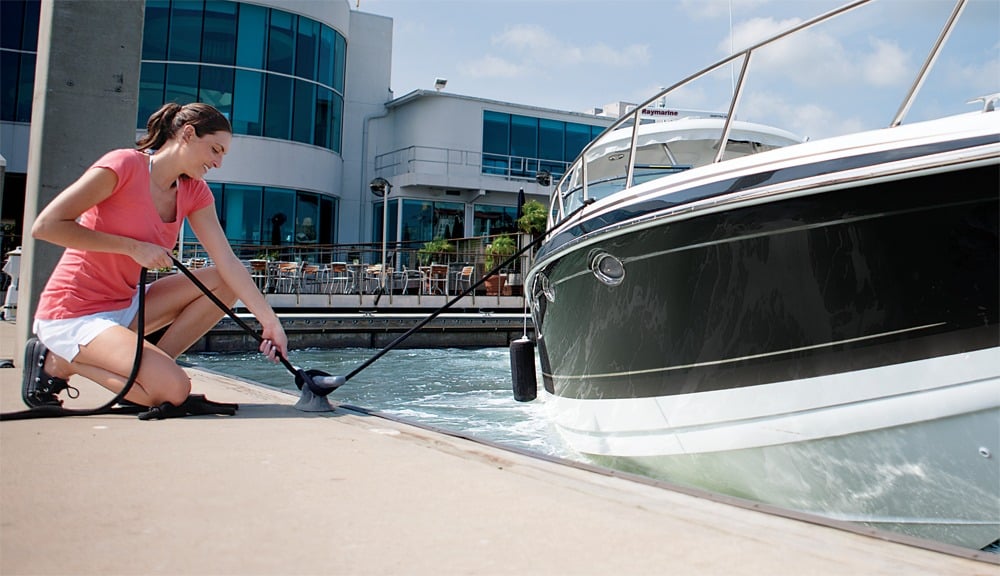 A woman tying off a rope to a boat on the dock