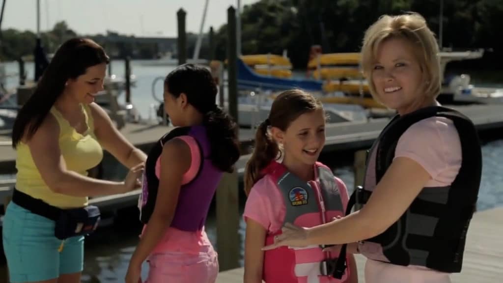 Two women fitting young girls with a life jacket.