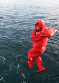 A person in a red survival suit jumping into the ocean